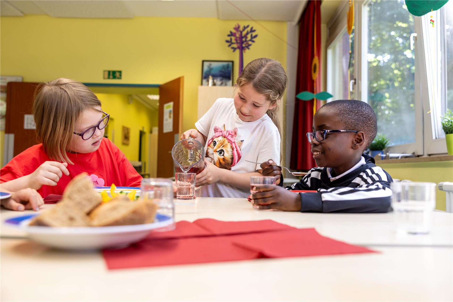 ein Mädchen schüttet Wasser in ein Glas.