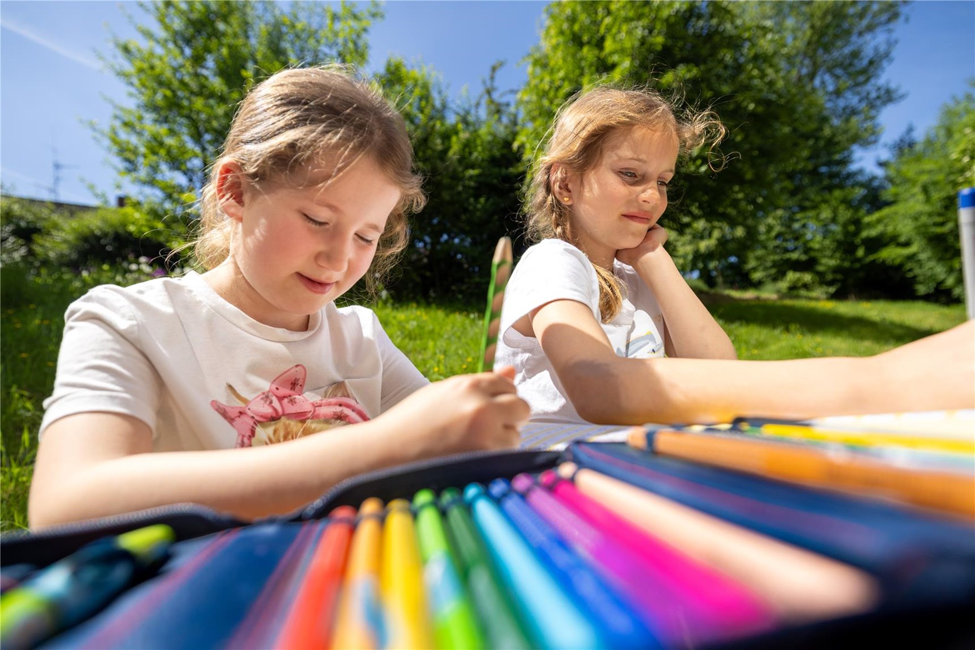 zwei Mädchen, die draußen malen.