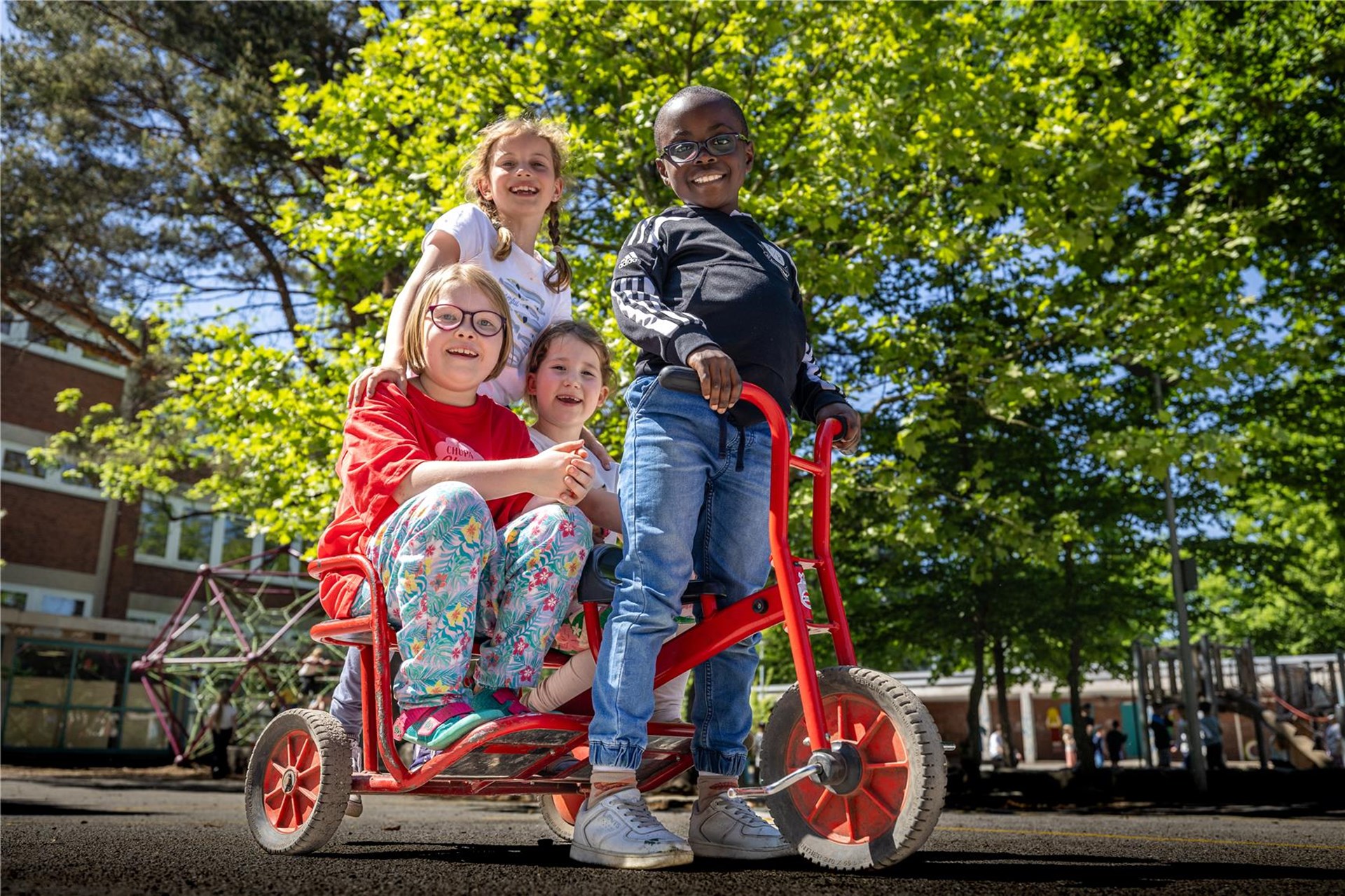 Vier Kinder sind auf einem Kinderfahrzeug.