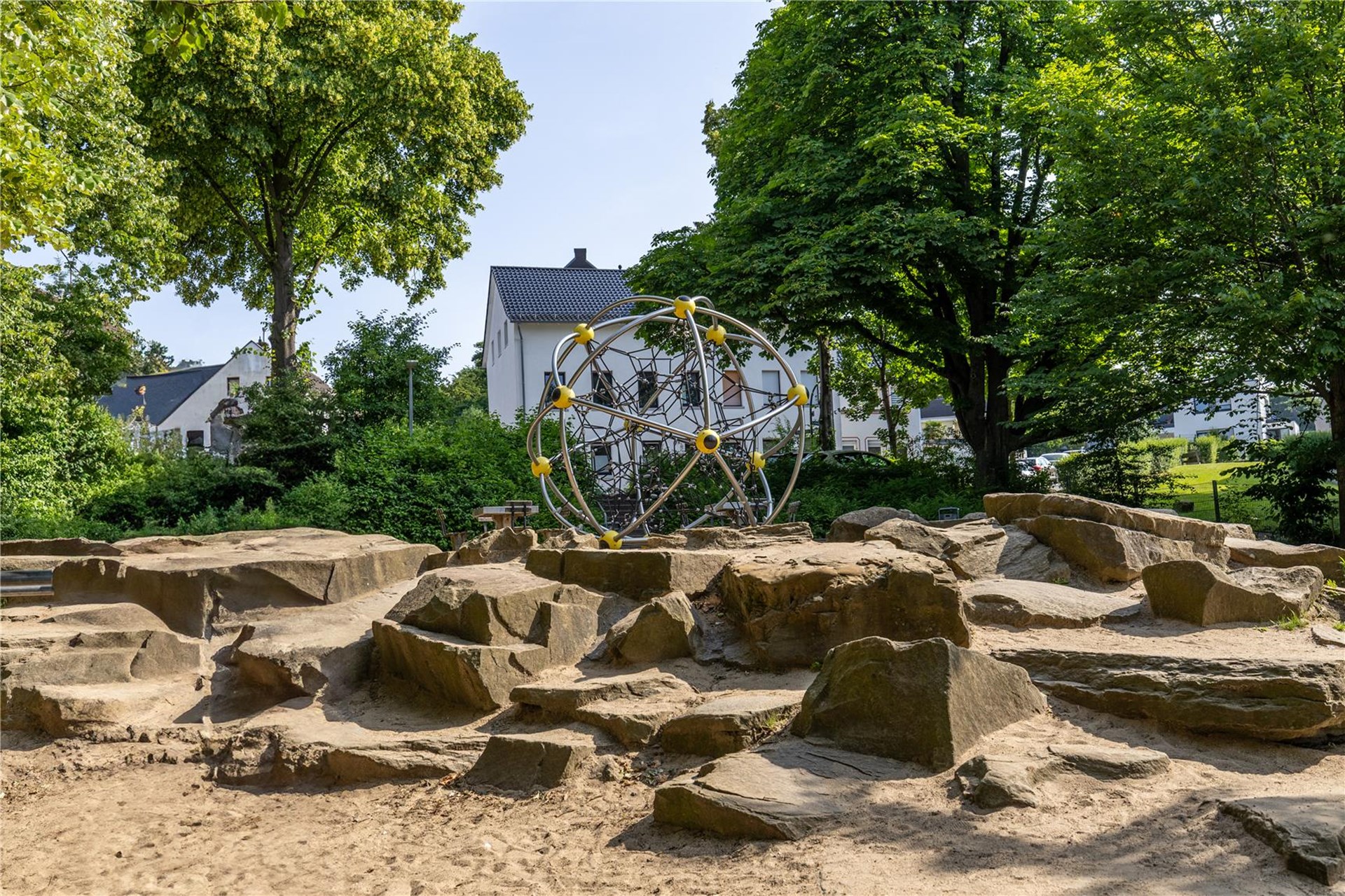 Klettergerüst, Schule und Schulhof unter altem Baumbestand